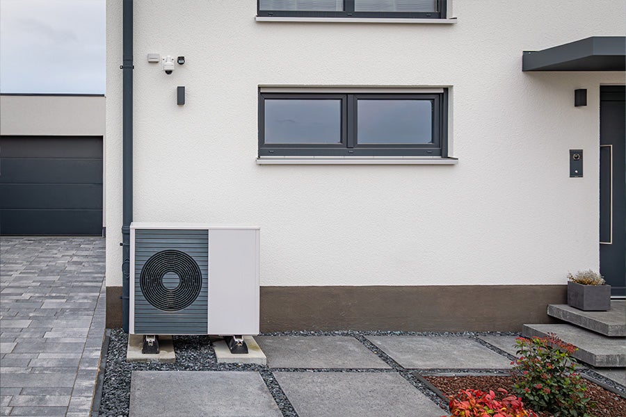 An air source heat pump in front of a detached house. 