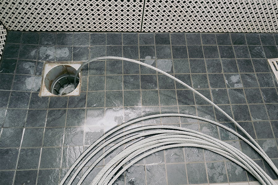 A large drain snake being used to unblock a shower drain.