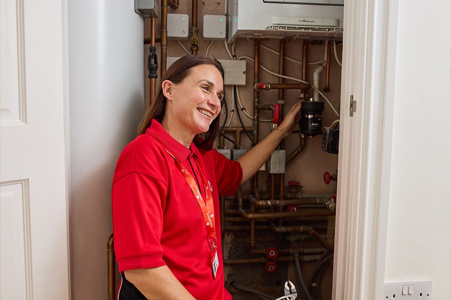 HomeServe engineer checking pipes on a boiler after responding to a boiler problem.