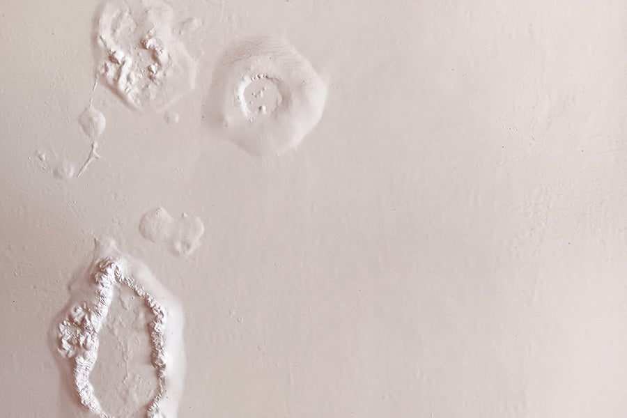 Bubbling paint on a white wall due to a hidden leak.