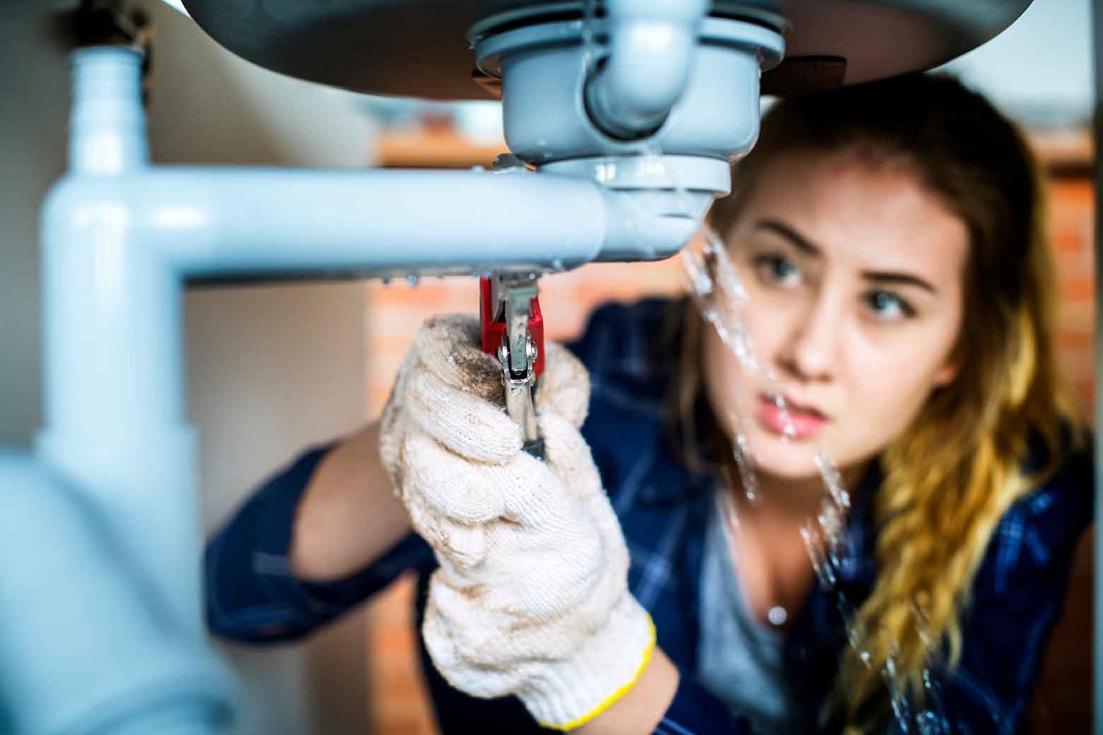 Woman fixing leaking pipe