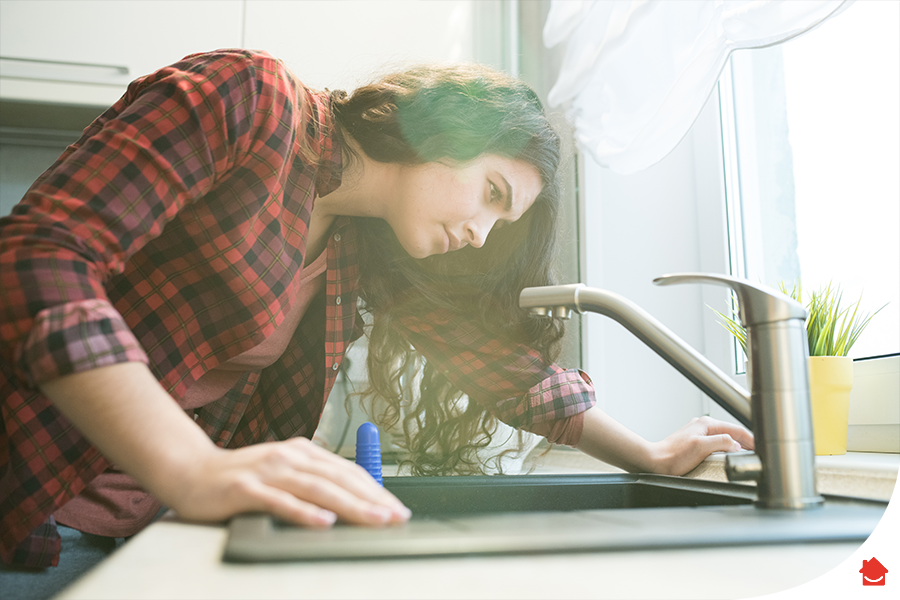 woman leaning over the kitchen sink -How to fix a blocked toilet