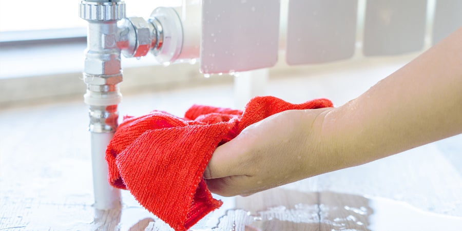 Person holding a cloth under a leaking radiator - How to fix a leaking radiator