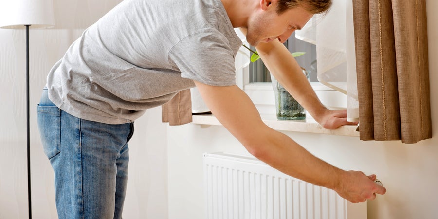 Man leaning over to look at radiator -how to measure a radiator