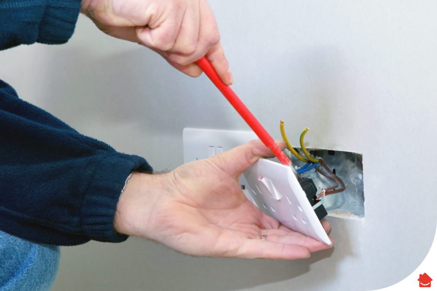 Person unscrewing a plug socket so they can change it.