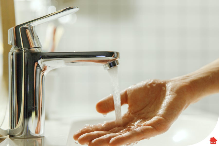 Image of a silver tap running water over someone's hand during a simple water flow test.