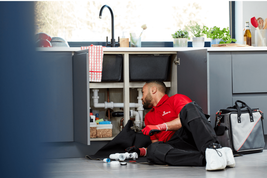 HomeServe engineer fixing a leak under the sink, a typical plumbing job, which would normally incur a plumbing repair cost