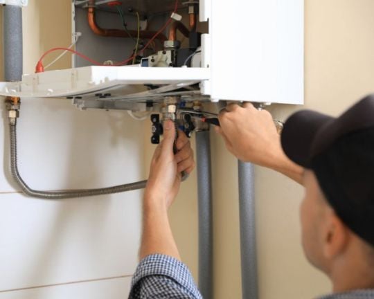An engineer connection a filling loop to a boiler