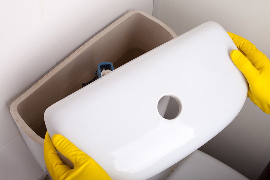 A plumber opening a toilet cistern to fix the water level
