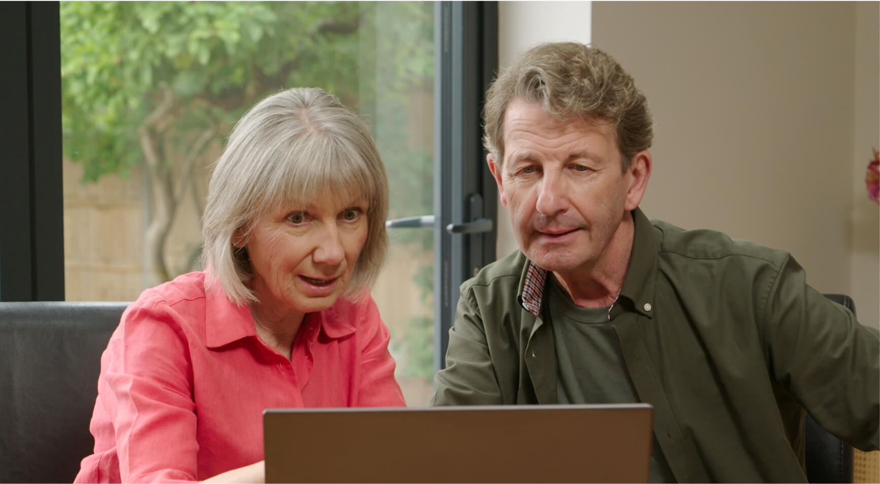 Homeowners sitting in front of a laptop looking at the HomeServe TV offer.