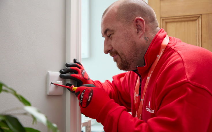 A HomeServe electrician repairing a light switch. 