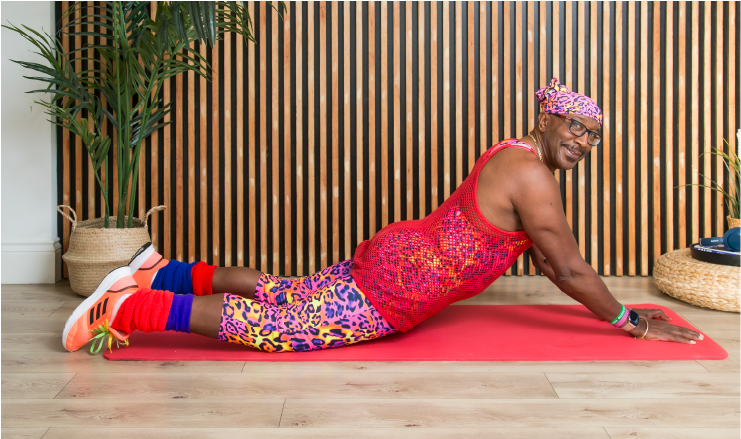 90's icon, Mr. Motivator lying on his front, in a stretch pose.