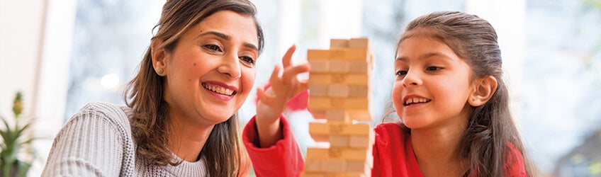 A woman and child playing with wooden stacking blocks