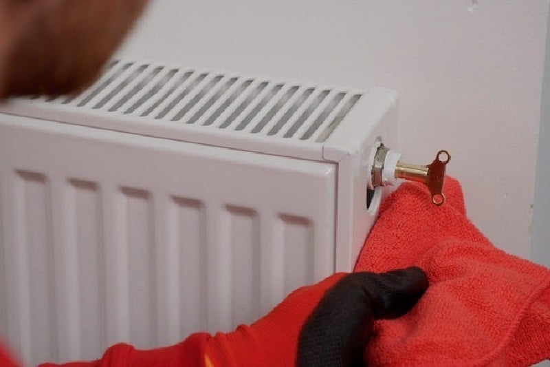 HomeServe engineer bleeding a radiator with radiator key