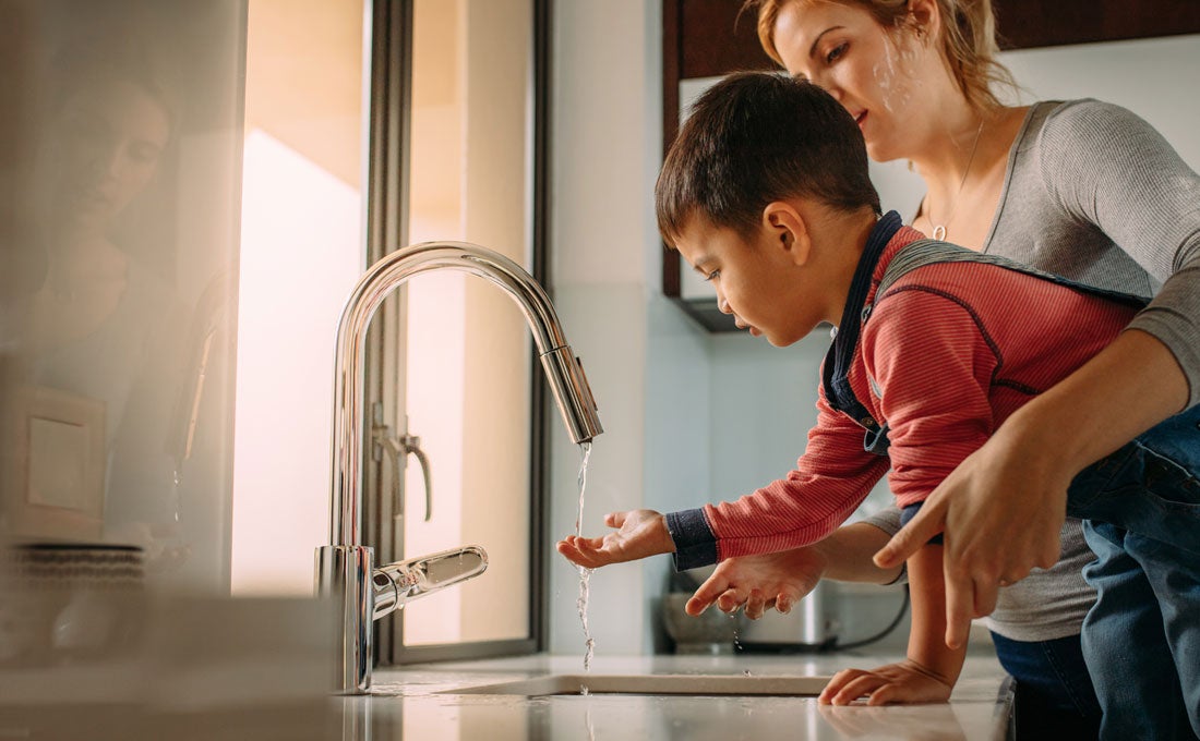 Child holds hand under sink tap