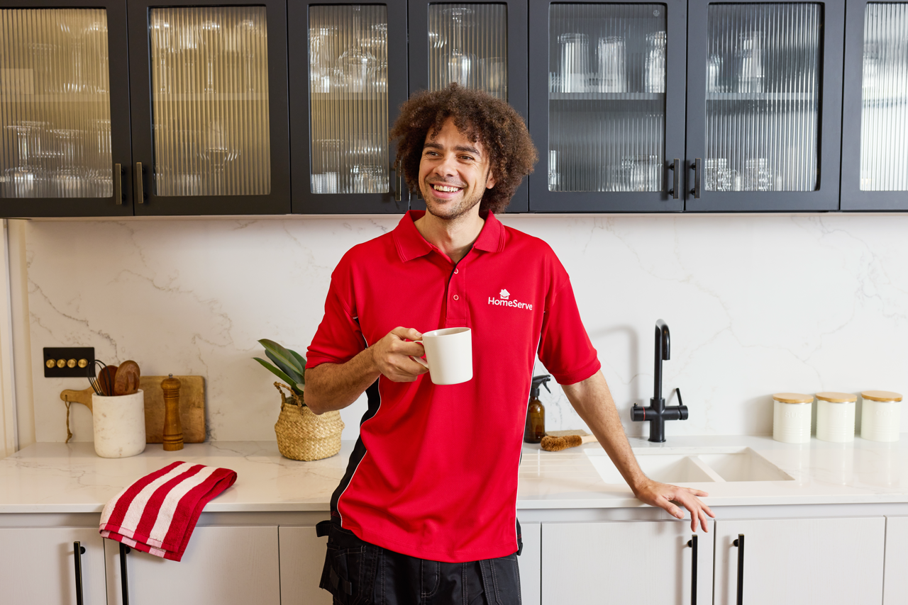 A smiling HomeServe plumber holding a cup of tea