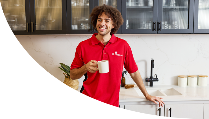 A smiling HomeServe plumber holding a cup of tea A smiling HomeServe plumber holding a cup of tea
