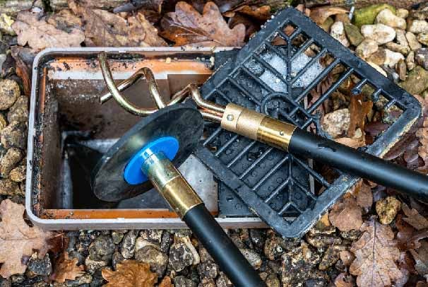 A blocked outside drain being unblocked by a drain rod