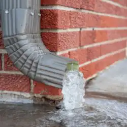 A blocked outside drain overflowing with water from a drain pipe