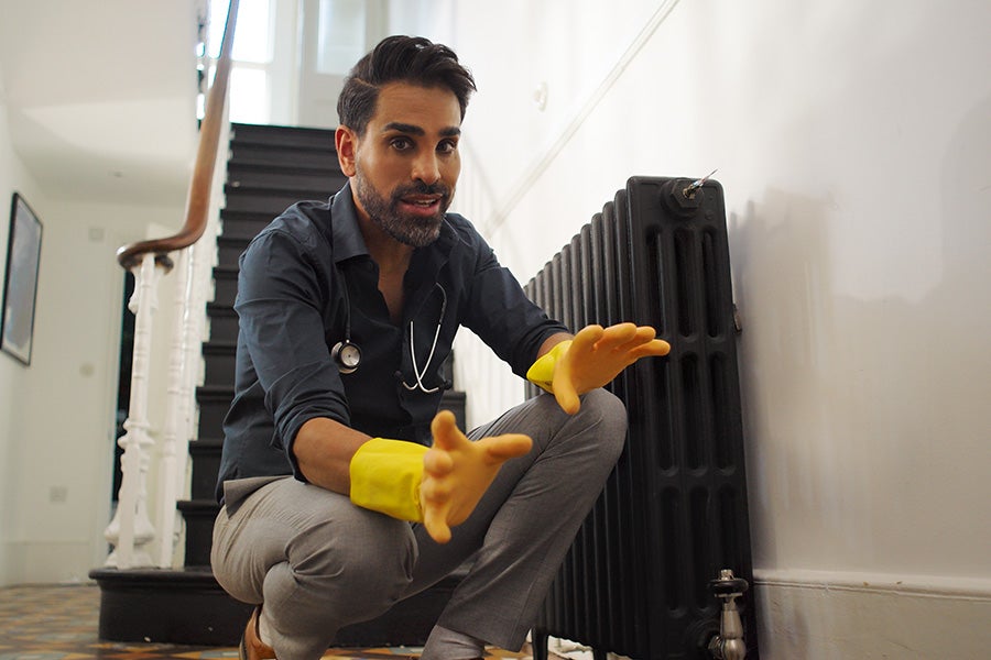 Dr Ranj Singh inspecting a radiator while wearing rubber gloves.