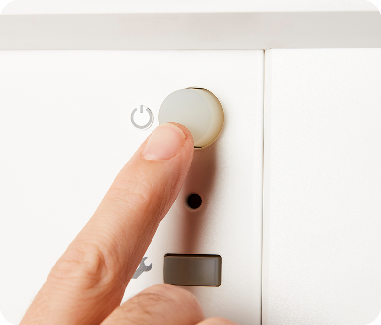 A person pressing the reset button on a gas boiler.