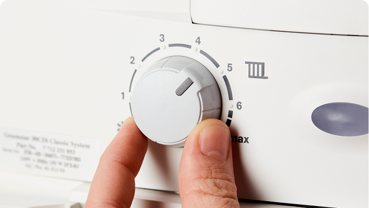 A person adjusting the boiler flow temperature dial on a gas boiler.